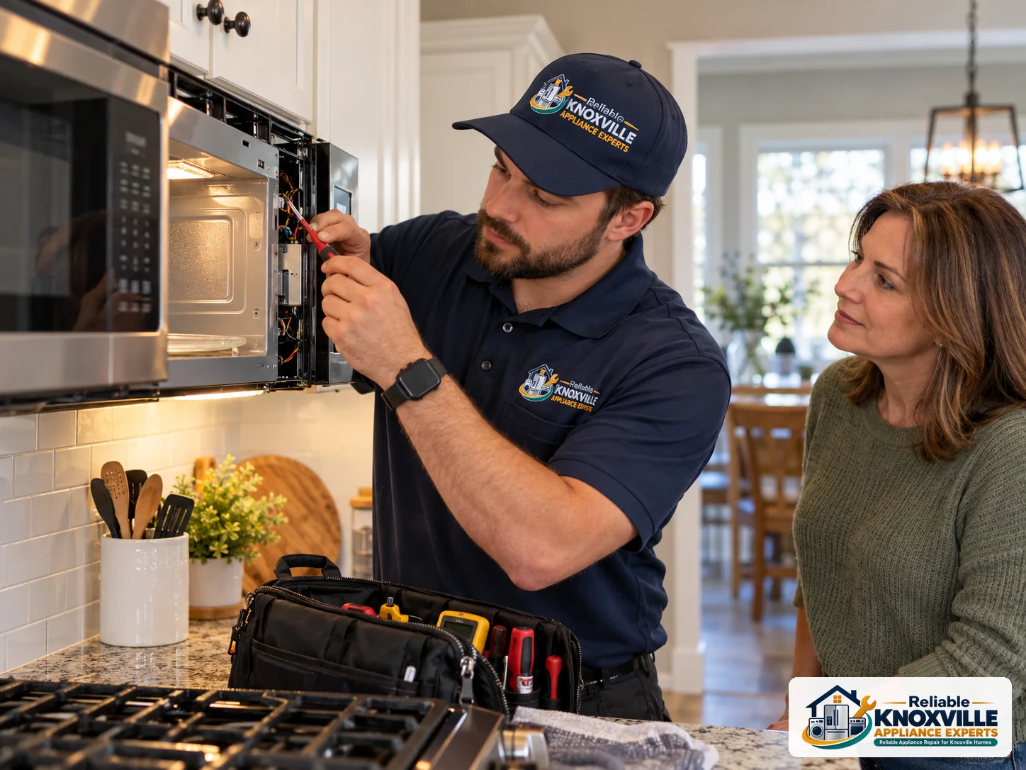 Technician carefully inspecting a built-in microwave in a home kitchen while a homeowner observes.